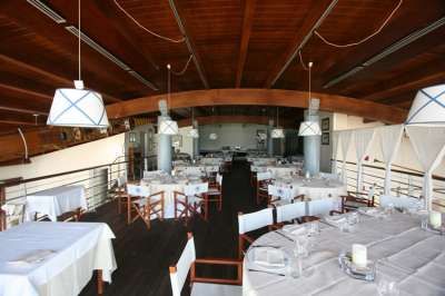 Un ristorante elegante con tavoli apparecchiati, sedie in legno e soffitto ad arco in legno.
