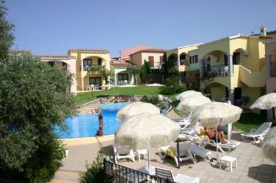 Complesso residenziale con piscina e lettini bianchi.