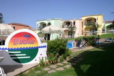 Un giardino con edificio colorato, sedie a sdraio e un cartello 