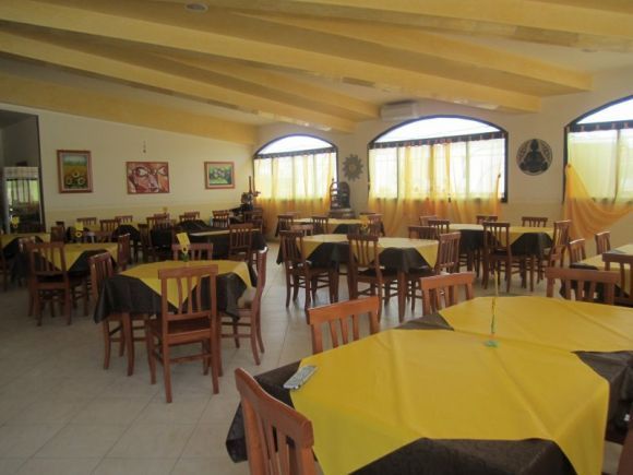Una sala da pranzo con tavoli apparecchiati in giallo.