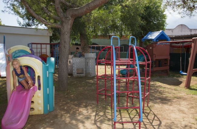 Bambino su scivolo in plastica in un parco giochi.