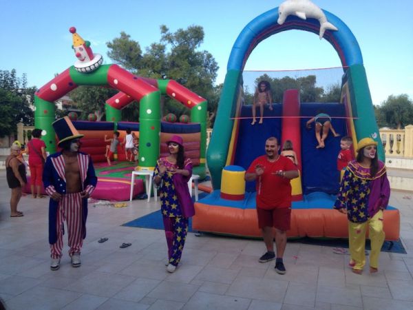 Clown e scivoli gonfiabili in un'area giochi all'aperto.