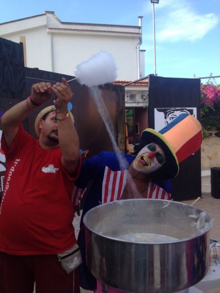 Clown e uomo preparano zucchero filato a una festa.