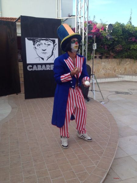 Clown giocoliere con palline su un palco all'aperto.
