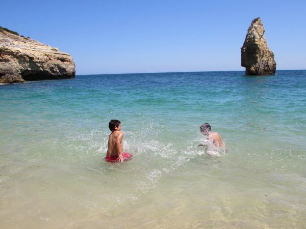 Due bambini giocano in mare vicino a scogli.