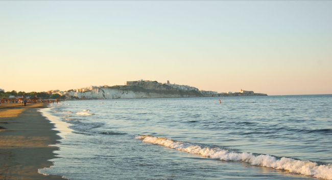 Spiaggia con mare calmo al tramonto.