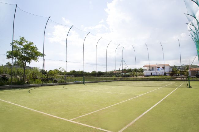 Un campo da tennis all'aperto con rete e recinzione.