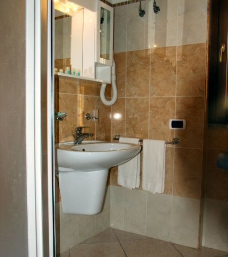 Bagno con lavabo, specchio, ripiani e asciugacapelli.