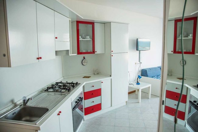 Cucina moderna bianca con dettagli rossi.