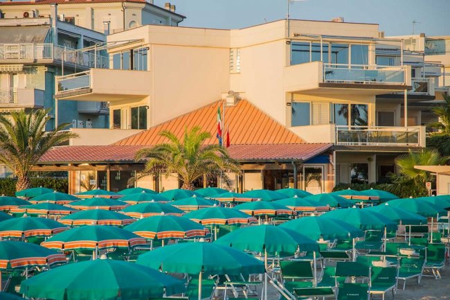 Edificio con ombrelloni verdi sulla spiaggia.