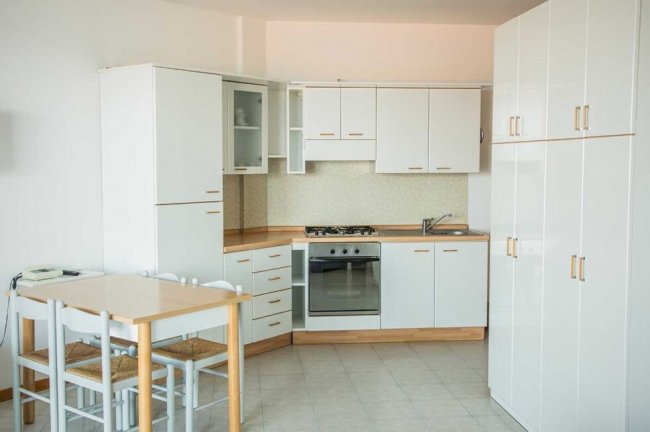 Cucina bianca moderna con tavolo e sedie.
