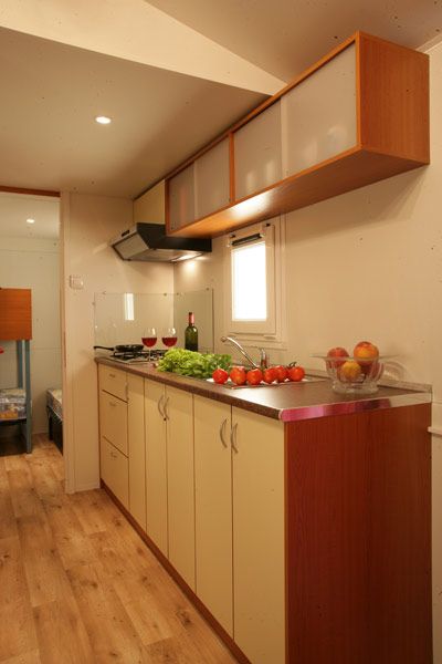 Cucina con mobile beige, stoviglie e frutta sul piano.