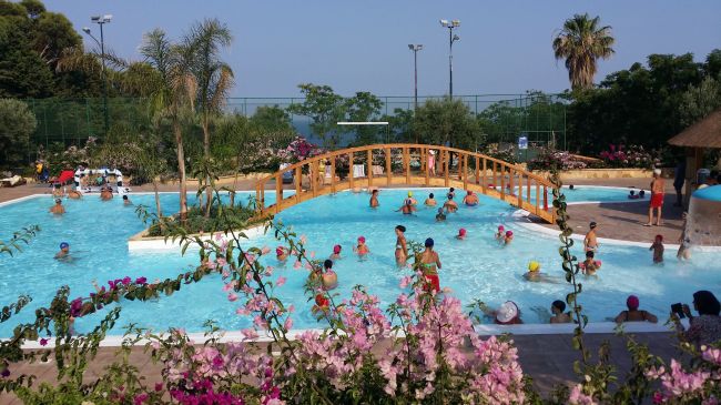Piscina con ponte di legno e persone che nuotano.