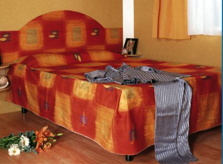Letto matrimoniale con copriletto colorato.