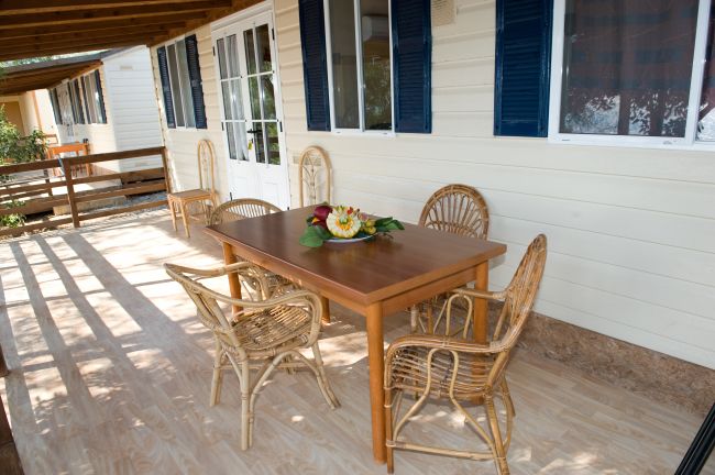 Veranda con tavolo in legno e sedie in vimini.