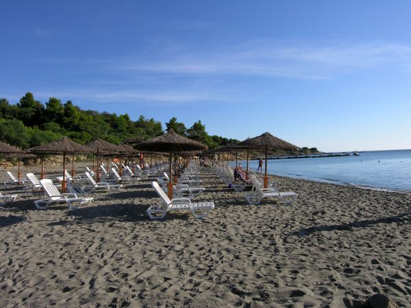 Spiaggia con lettini e ombrelloni di paglia.