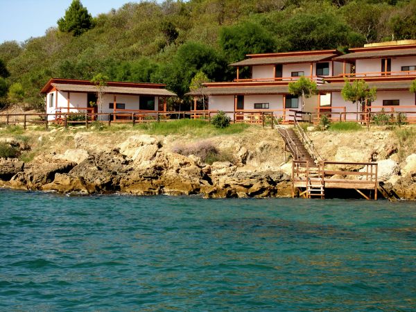 Case fronte mare con balconi su scogliera verde.