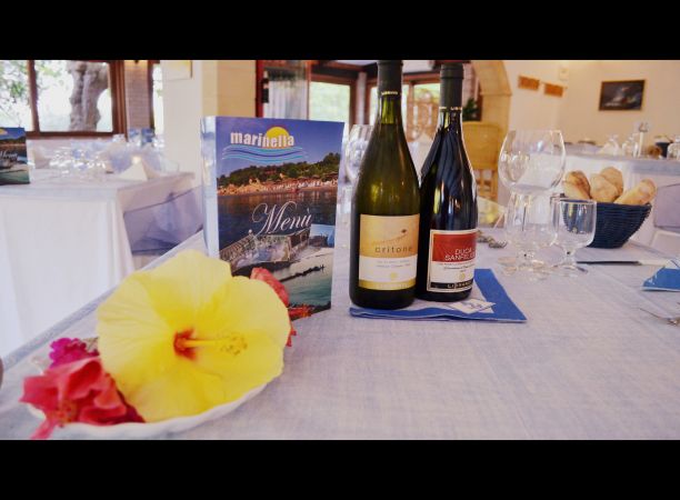 Bottiglie di vino e un menu su un tavolo elegante con fiori.