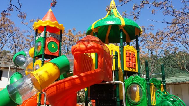 Colorato parco giochi all'aperto con scivoli e torrette.