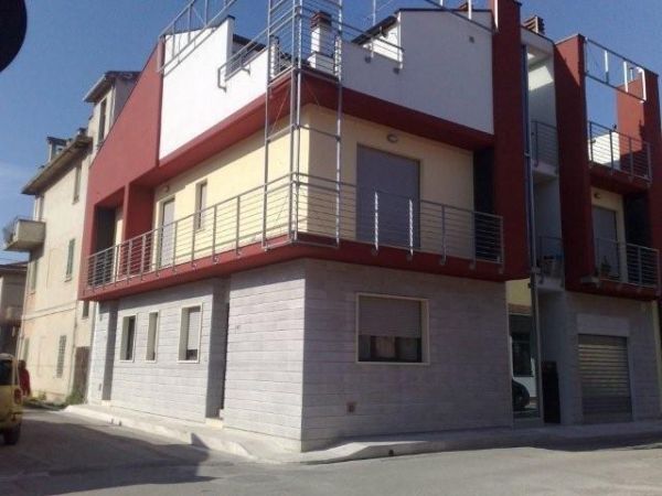 Edificio moderno a due piani con balcone in metallo e pareti rosse e bianche.