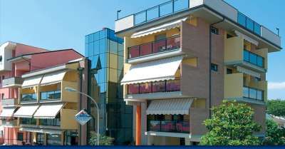 Edifici moderni con balconi e finestre ampie, sotto un cielo azzurro.
