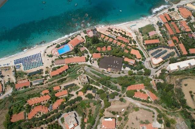 Vista aerea di un complesso turistico con edifici e una spiaggia.
