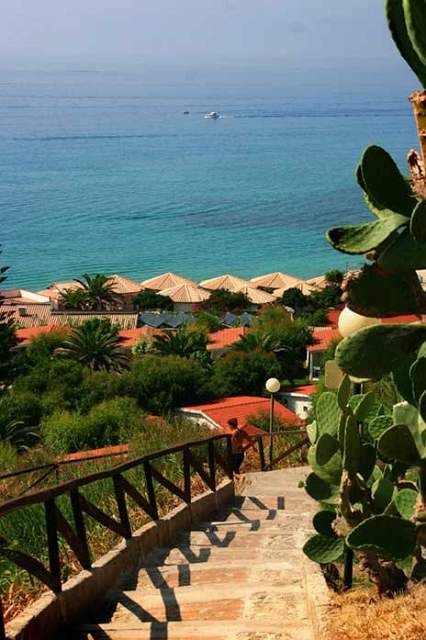 Scalinata con ringhiera che scende verso il mare, cactus ai lati.