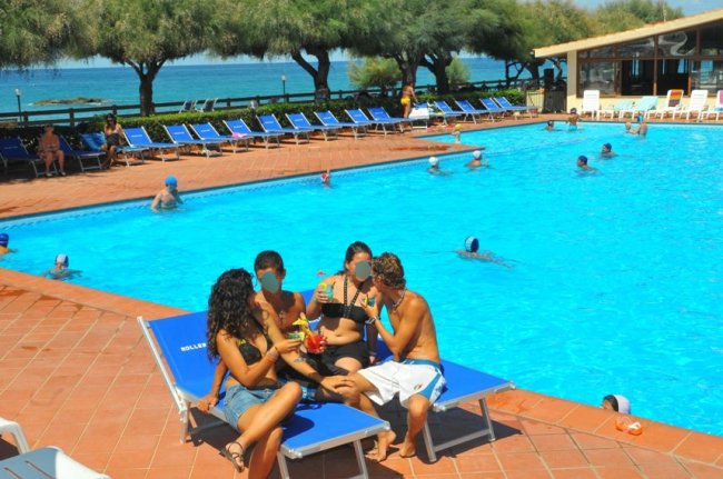 Persone rilassate su lettini accanto alla piscina.
