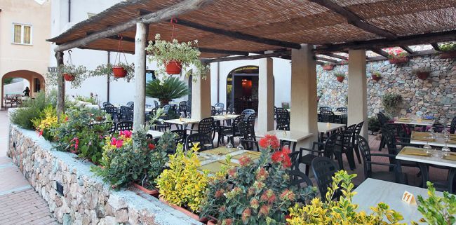 Ristorante all'aperto con tavoli e piante colorate.