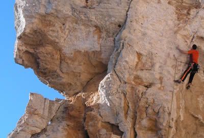 Uomo arrampica su una grande roccia.