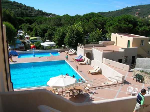 Piscina all'aperto con lettini, circondata da vegetazione.