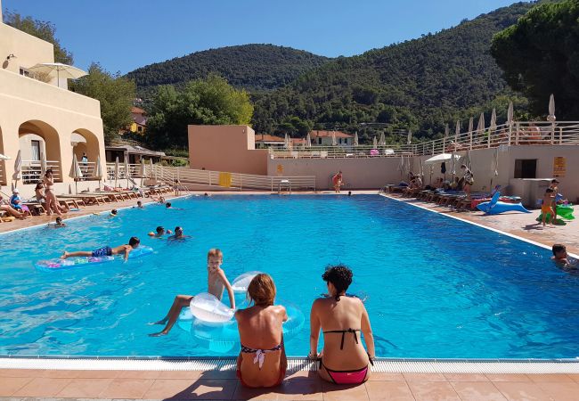 Persone rilassate a bordo piscina con montagne sullo sfondo.