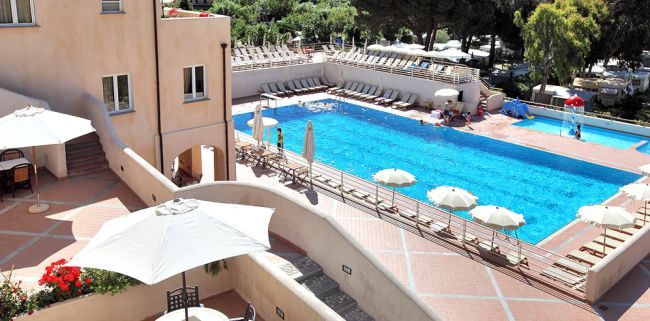 Piscina all'aperto con lettini e ombrelloni bianchi.