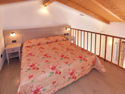 Letto matrimoniale con copriletto floreale in mansarda.