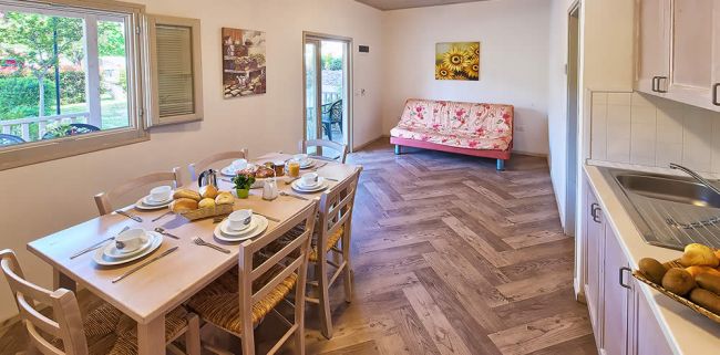 Sala da pranzo con tavolo apparecchiato e cucina.