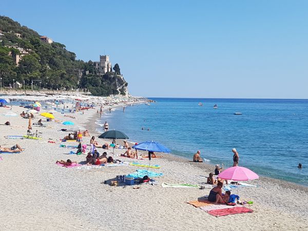 Spiaggia affollata con ombrelloni colorati e mare.