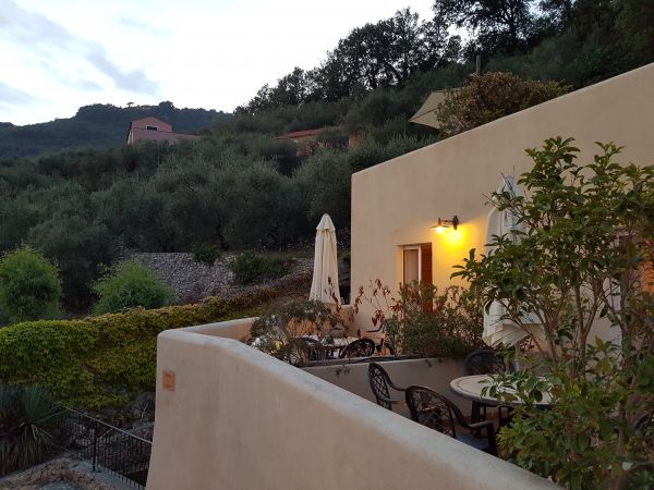 Terrazza con tavolini e sedie, circondata da natura.