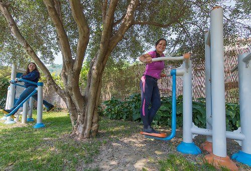 Due donne fanno esercizio all'aperto con attrezzi fitness.