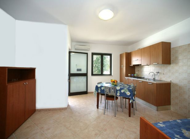 Cucina con tavolo da pranzo, credenza marrone e vista sul giardino.