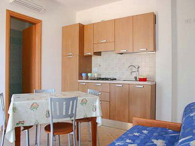 Cucina con tavolo da pranzo, sedie, mobili in legno e divano blu.