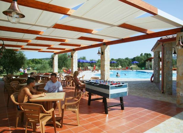 Due persone sedute a un tavolo sotto un pergolato vicino a una piscina.