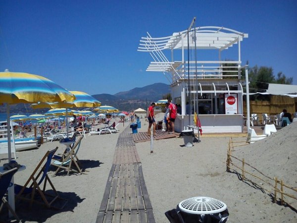 Spiaggia con chiosco e ombrelloni colorati.
