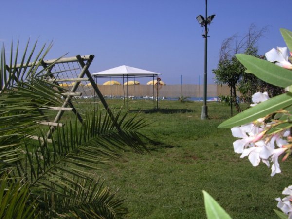 Prato con altalena e gazebo davanti al mare.