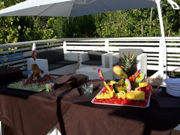 Tavoli con frutta esotica e sedute bianche all'aperto.
