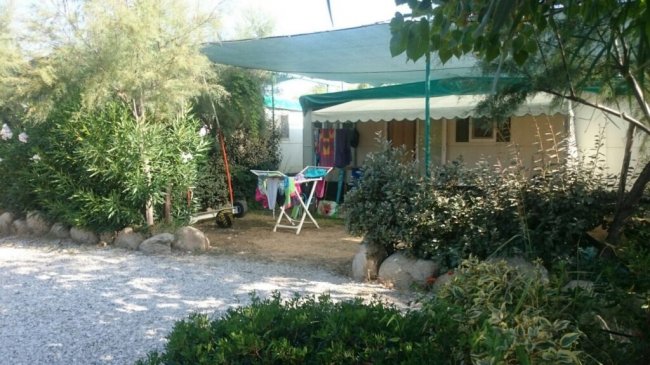 Spazio verde con roulotte e area ombreggiata.