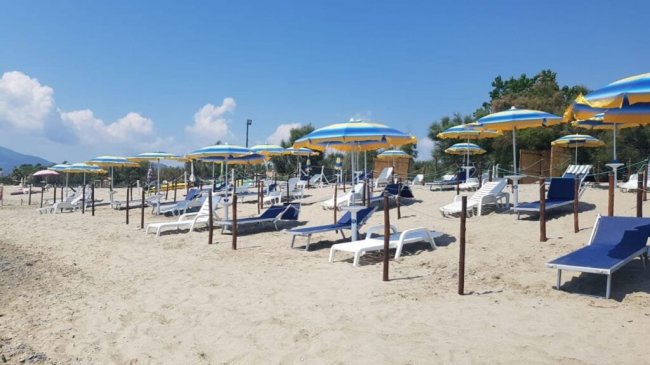 Ombrelloni e lettini sulla spiaggia sabbiosa.