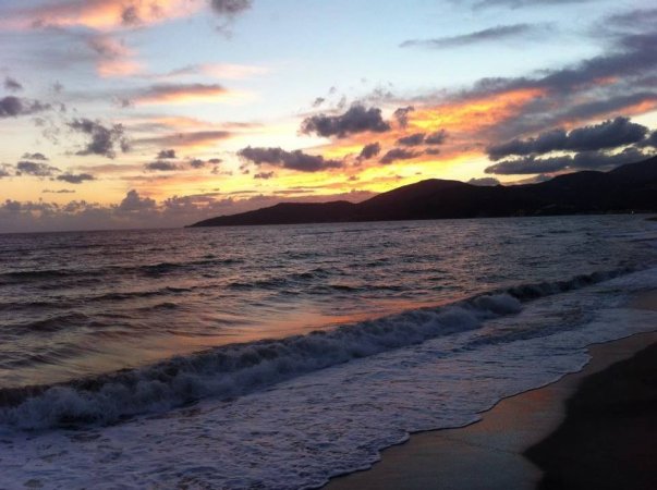 Tramonto su una spiaggia con onde e cielo colorato.