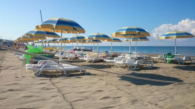 Sdraio e ombrelloni gialli e blu sulla spiaggia.