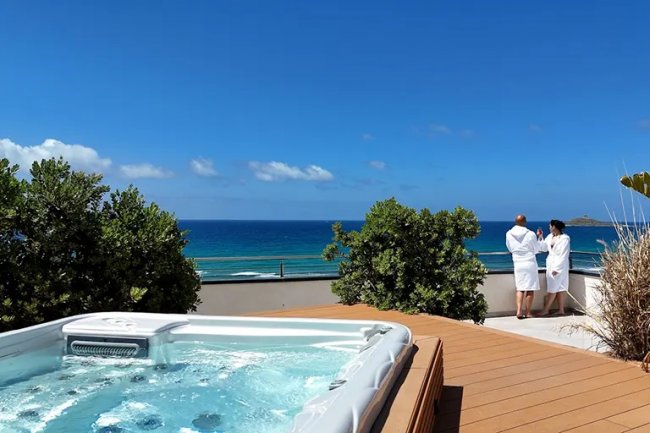 Terrazza con jacuzzi e vista mare, due persone in accappatoio.