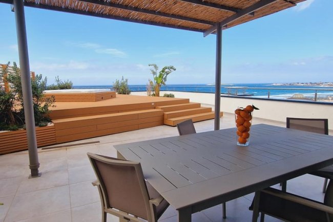 Terrazza con tavolo, sedie e vista mare.